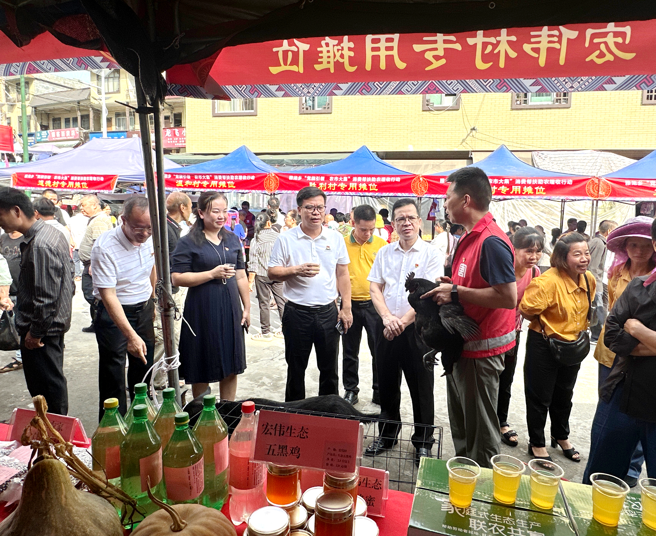 圖為駐村第一書記黃福元帶領宏偉村參加雅龍鄉農市大集，向觀展人員介紹宏偉生態五黑雞.png